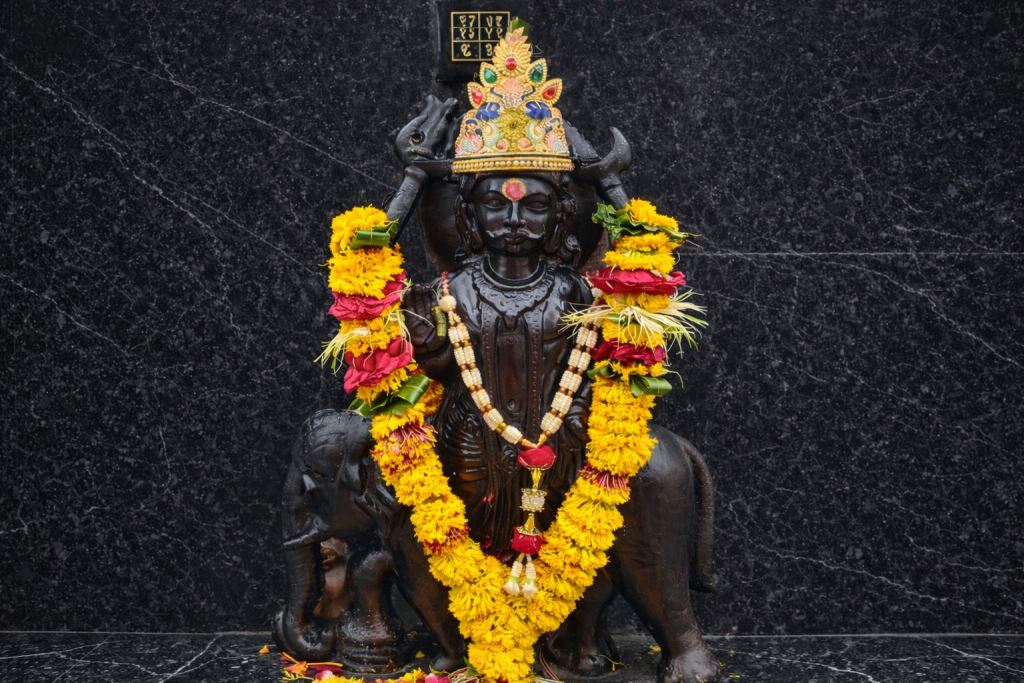 Shani Dev — shrine murthi with floral garlands and crown